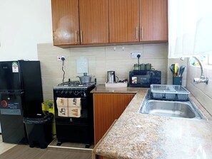 Eine Küche mit Holzschränken, einem Herd, einem Kühlschrank und einer Spüle.