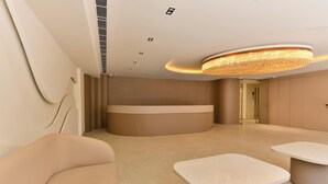 A modern hotel lobby with a reception desk, seating area, and a large chandelier. - Melange Hotel (Gurugram)