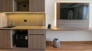 A modern kitchen with built-in appliances, a large flat-screen TV, and a minimalist design. - Melange Hotel (Gurugram)