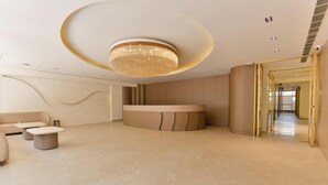 A modern reception area with a circular desk, seating, and a unique ceiling light fixture. - Melange Hotel (Gurugram)