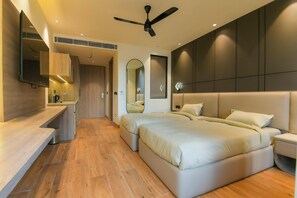 A modern bedroom with a large bed, bedside tables, a ceiling fan, and a mirror. - Melange Hotel (Gurugram)