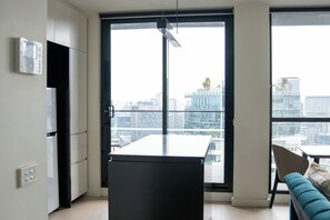 A modern kitchen with a large window, a dining area with a table and chairs, and a view of the cityscape. - Modern high rise apt, with balcony, secure parking (Southbank)