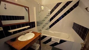 Un baño con tocador de madera, un lavabo blanco, un espejo, un perchero para toallas y una bañera.