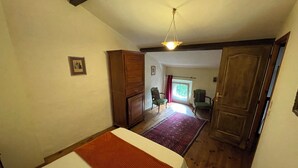 Un dormitorio con cama, armario de madera, silla, puerta y vistas al exterior.