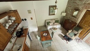 Una cocina con comedor, un sofá, una televisión y una pared de piedra.