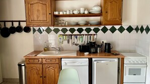 Una cocina con armarios de madera, un lavamanos, lavavajillas, estufa y una mesa de comedor con sillas.