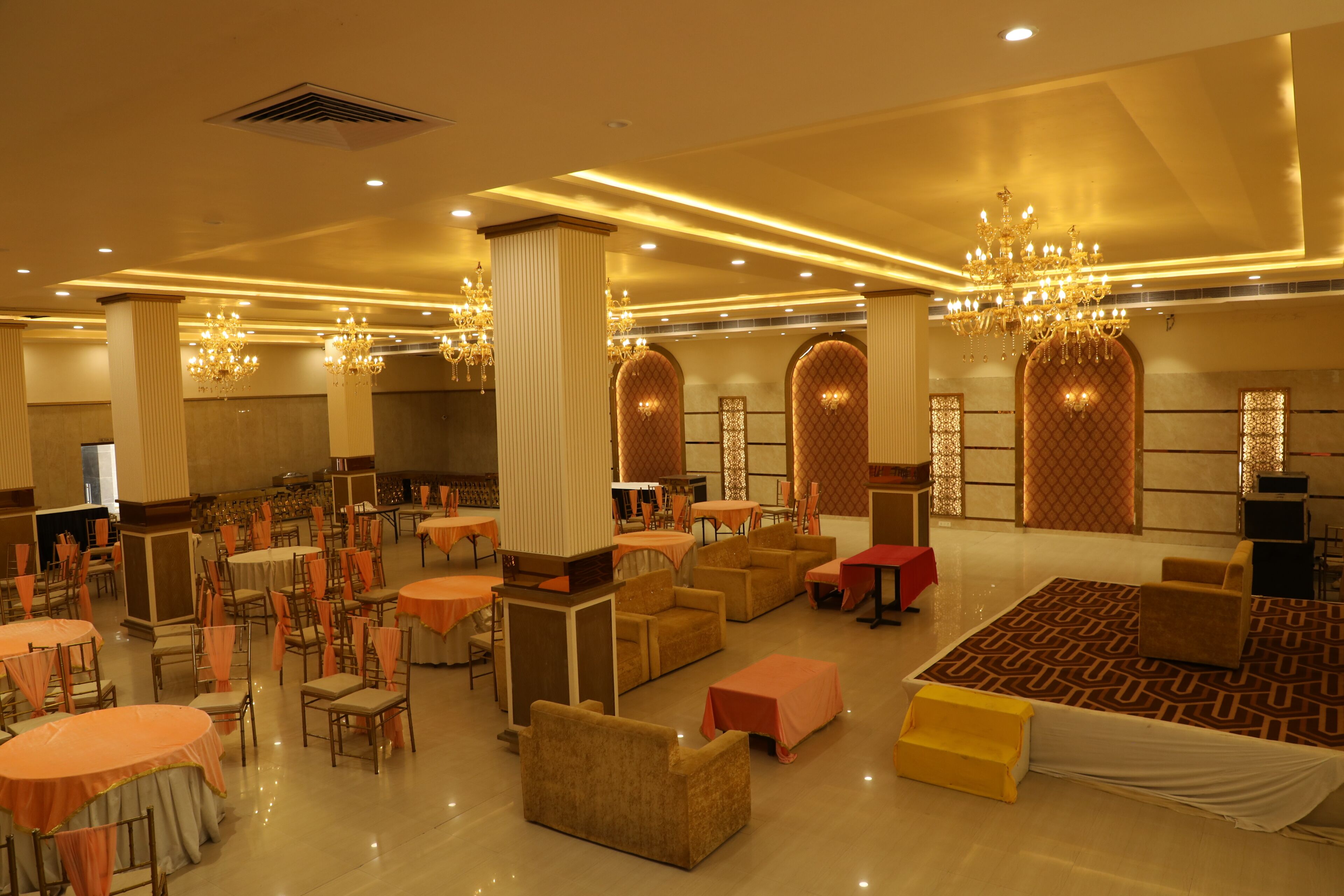 A spacious hotel lobby with multiple seating areas, chandeliers, and a patterned carpet.