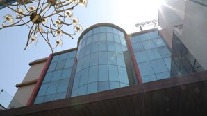 Um edifício moderno com fachada de vidro, deck de madeira e lustre metálico.