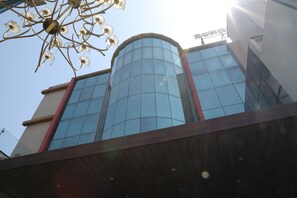 A modern building with a glass facade, a wooden deck, and a metal chandelier. - Sona Pristine Hotel And Resort (Dera Bassi)