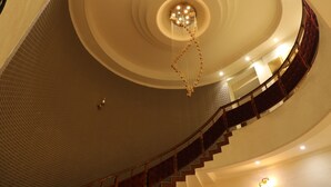 Uma escadaria imponente com um candelabro, teto curvilíneo e parede de tijolos.