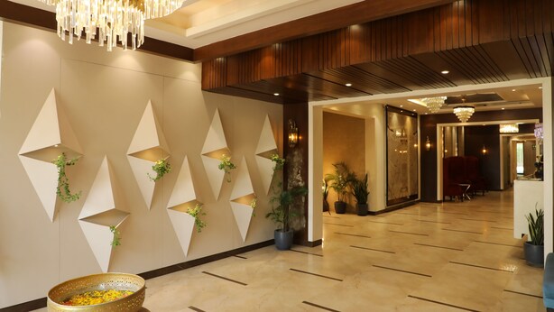 Um hall amplo com um lustre moderno, design geométrico nas paredes e plantas em vasos.