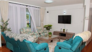 Una sala de estar con un conjunto de sofá, una mesa de centro y un televisor montado en la pared.