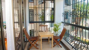 Un balcón con una mesa, sillas, una planta en maceta y vistas al exterior.