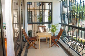 Uma varanda com mesa e cadeiras, um vaso de planta e vista para o exterior.