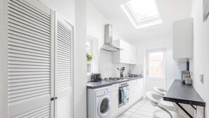 Une cuisine moderne dotée d’un lave-linge encastré, d’un plan de travail noir et d’une fenêtre de toit.
