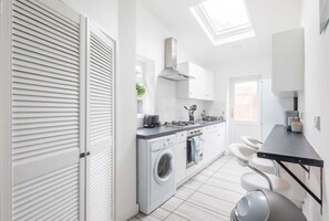 Eine moderne Küche mit eingebauter Waschmaschine, schwarzem Arbeitsplatz und einem Oberlicht.