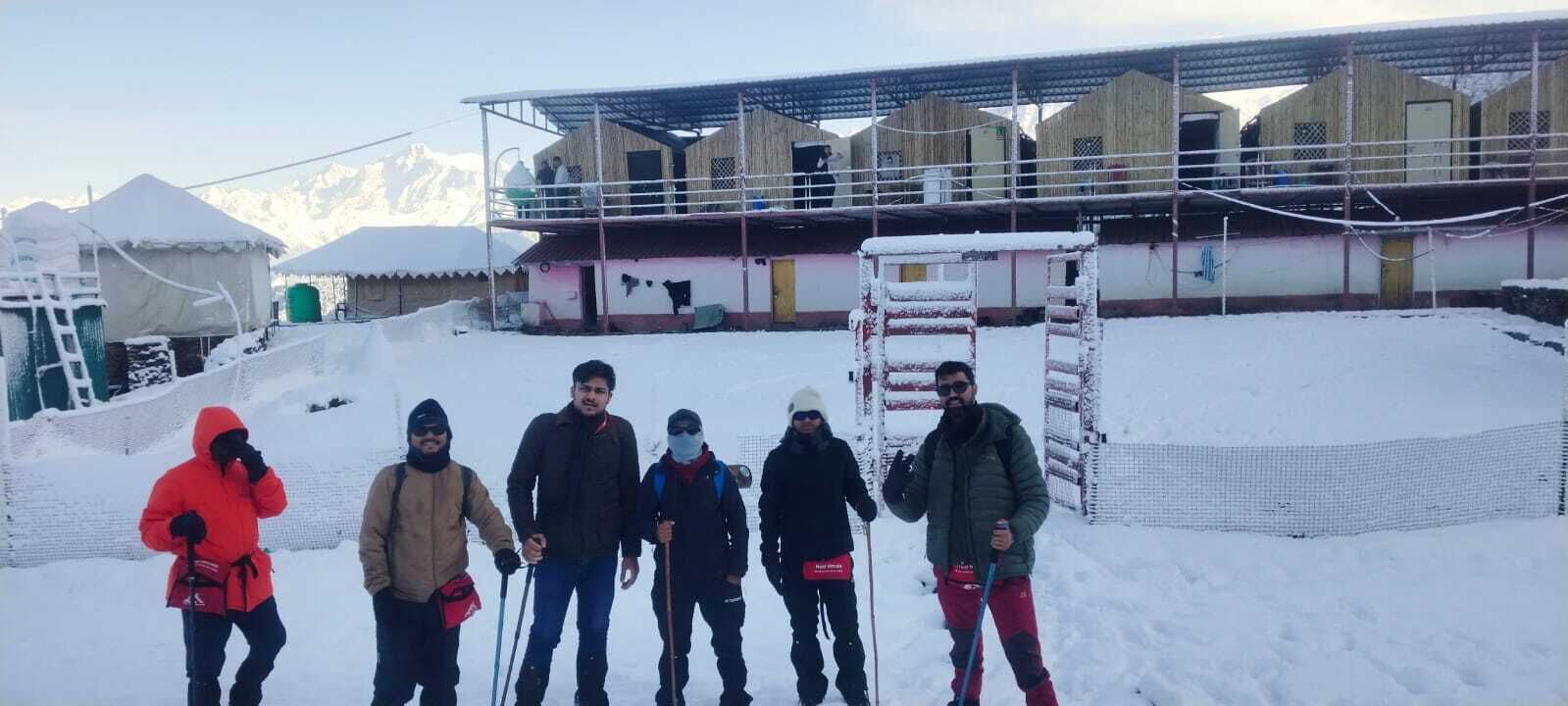 A group of people standing in a snowy outdoor area with a building in the background.