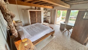 Quarto com cama, escrivaninha e vista para o exterior.