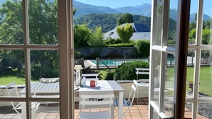 A patio with outdoor furniture, a pool, and a view of mountains.
