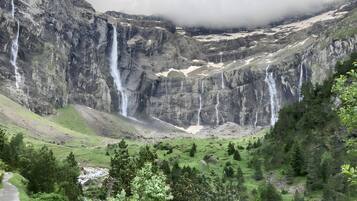 A mountainous landscape with multiple waterfalls, a valley with greenery, and a river.