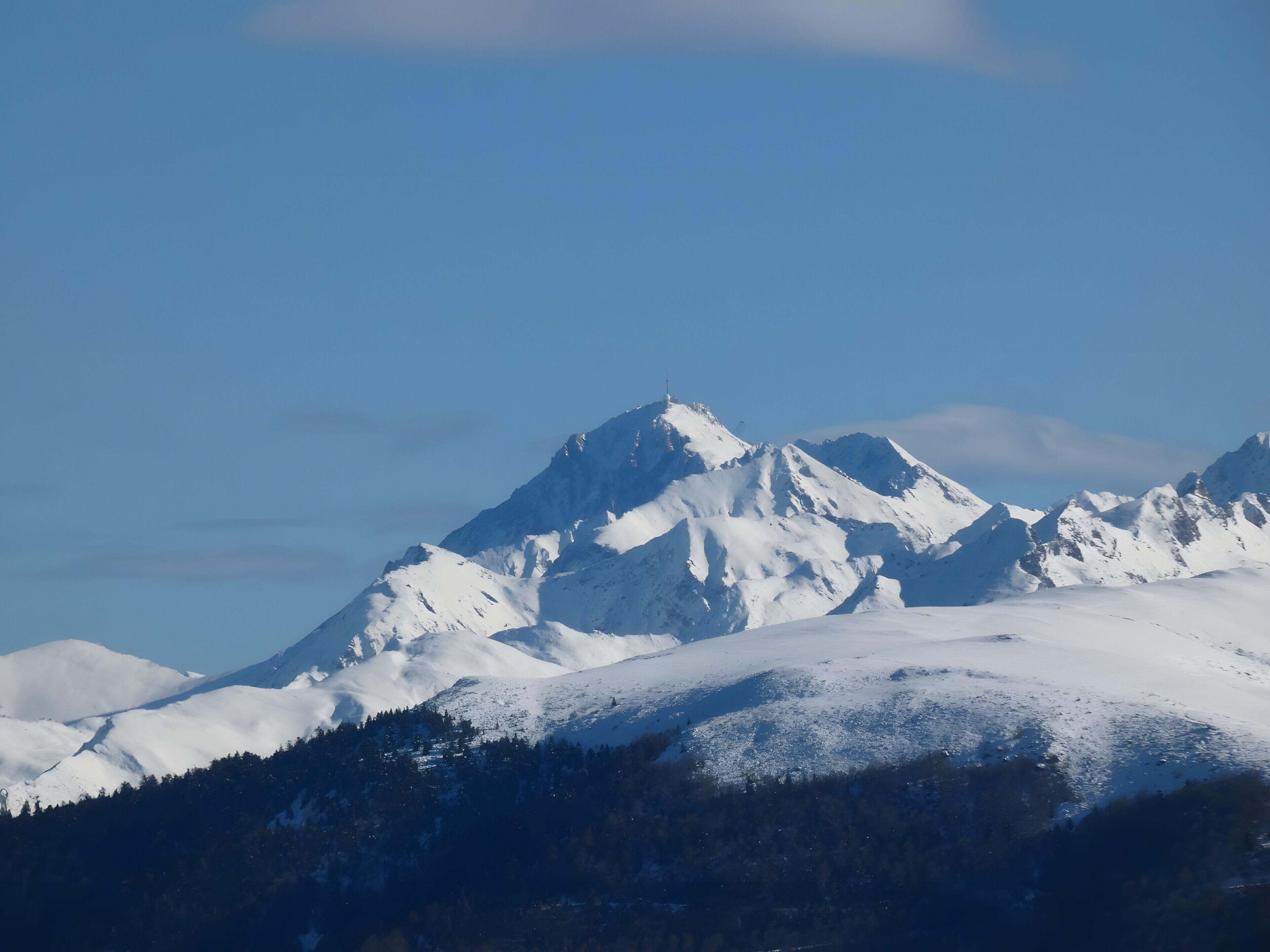 Un pico montañoso cubierto de nieve con cielo despejado.