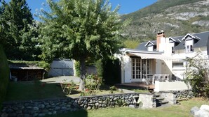 A house with a stone wall, a tree, and a clear view of the surrounding landscape.