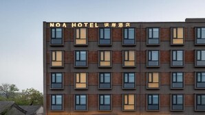 A multi-story hotel with a modern facade, featuring a series of windows and a prominent signage at the top.