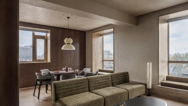 A modern living room with a sofa, dining table, chairs, and large windows.