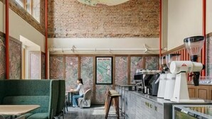 A restaurant with a high ceiling, exposed brick walls, and a large decorative hanging light.