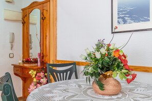 A dining table with a lace tablecloth, a copper vase with flowers, a wooden cabinet, and a framed picture on the wall. - Apartment 'Famacosta' with Balcony (Benidorm)