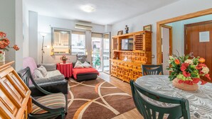 En hyggelig stue med sofa, stole, spisebord og et træskab med et fjernsyn.