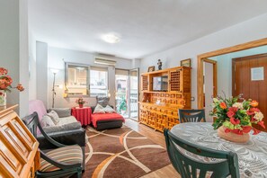 A cozy living room with a sofa, chairs, a dining table, and a wooden cabinet with a television. - Apartment 'Famacosta' with Balcony (Benidorm)