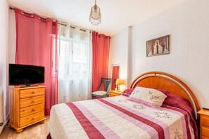 A bedroom with a bed, a dresser, a television, and a window with curtains. - Apartment 'Famacosta' with Balcony (Benidorm)