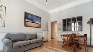 Ein modernes Wohnzimmer mit einem grauen Sofa, einem Holzesstisch und einem Gemälde mit einer Strandansicht.