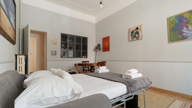 Ein Schlafzimmer mit einem Bett, einem Sofa, einem Schreibtisch und einem Fenster.