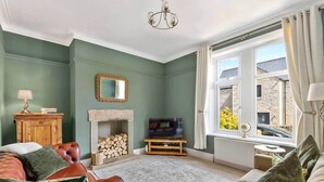 A living room with a fireplace, a television, and a view of the outside. - Period Character Cottage Haworth (Haworth)