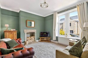 Ein Wohnzimmer mit Kamin, Fernseher und Blick ins Freie.