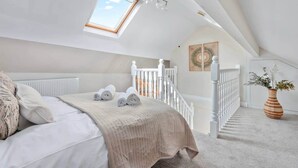 A bedroom with a skylight, a bed with rolled towels, a staircase, and a vase with plants. - Period Character Cottage Haworth (Haworth)
