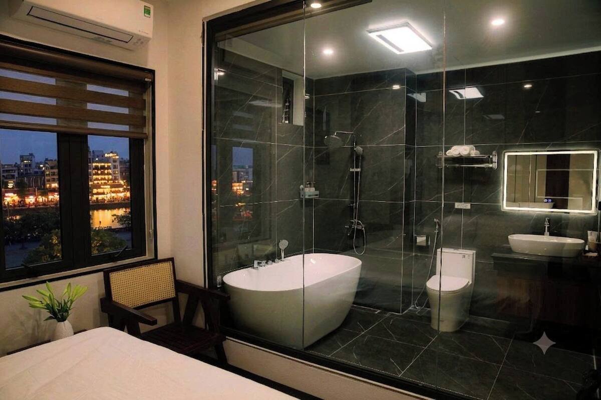 A modern bathroom with a glass-enclosed shower, a freestanding bathtub, and a toilet.