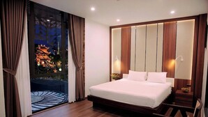 A hotel room with a large bed, wooden headboard, two bedside lamps, a nightstand, and a view of a traditional building outside. - Kevin Hung Hotel (Hoa Lu)