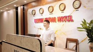 A hotel reception desk with clocks indicating different time zones, a reception sign, and a plant. - Kevin Hung Hotel (Hoa Lu)