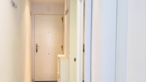 A hallway with white walls, a marble floor, and a door at the end. - Suite Marina Sol (Casares Costa)