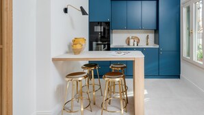 A kitchen with blue cabinets, a white countertop, and three gold stools. - Cozy lodging in Málaga (Málaga)