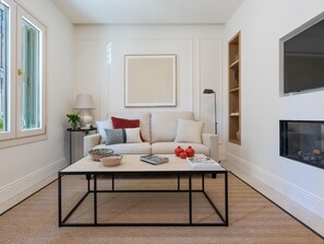A living room with a sofa, coffee table, lamp, and a fireplace. - Cozy lodging in Málaga (Málaga)