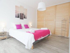 Une chambre à coucher comprenant un lit, une table de chevet, une armoire et un luminaire suspendu.