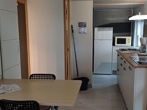 Een kleine keuken met een magnetron, fornuis en spoelbak.