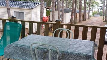 A deck with a table and chairs, surrounded by trees and mobile homes.