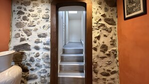 A stone wall with a wooden-framed doorway leading to a staircase.