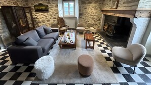 A living room with a stone wall, a fireplace, a checkered floor, a sofa, a coffee table, and a chair.