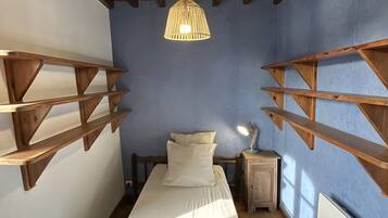 Ein Schlafzimmer mit einem Bett, Holzregalen, einer Hängeleuchte und einer Heizung.